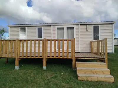 a house with a large porch and a wooden deck at Mobil home dans camping 3 étoiles in Saint-Papoul