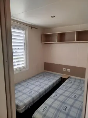 two beds in a small room with a window at Mobil home dans camping 3 étoiles in Saint-Papoul