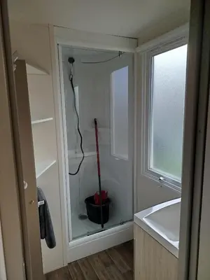 a bathroom with a glass cabinet with a vacuum at Mobil home dans camping 3 étoiles in Saint-Papoul