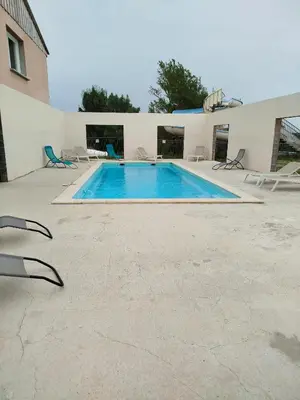 a large swimming pool with chairs and a building at Mobil home dans camping 3 étoiles in Saint-Papoul