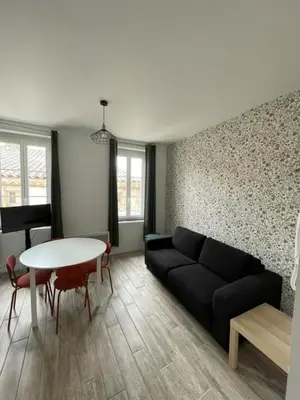 a living room with a black couch and a table at Les Halles d'Isa et Thomas in Narbonne
