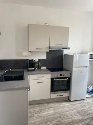 a kitchen with white appliances and white cabinets at Les Halles d'Isa et Thomas in Narbonne
