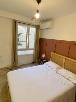 a bedroom with a large white bed with a window at Les Halles d'Isa et Thomas in Narbonne