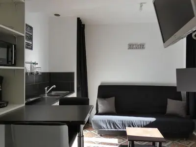a living room with a black couch and a sink at Hebergement privatif coeur de village in Maury