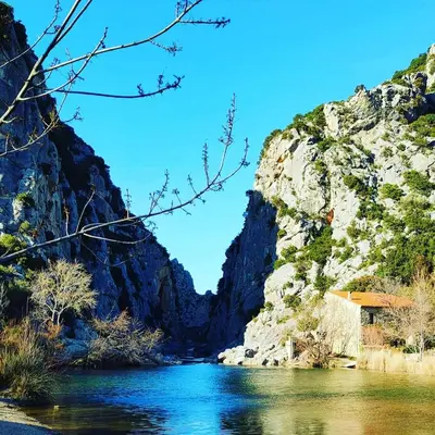a river in a canyon with a building on the side at Hebergement privatif coeur de village in Maury