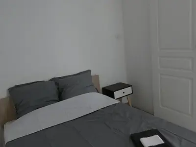 a bedroom with a bed and a nightstand next to a door at Hebergement privatif coeur de village in Maury