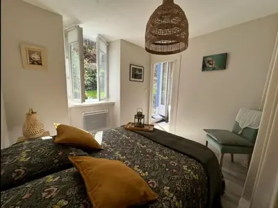 a bedroom with a bed and a chair and windows at Cottage by River with Spa near Carcassonne in Caudebronde