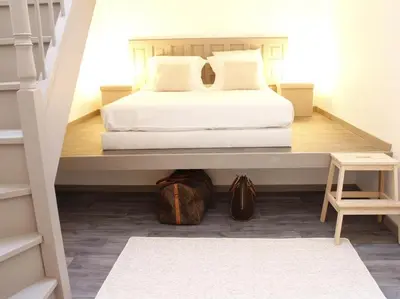 a bedroom with a white bed and a staircase at Maison Bacou cité 1 in Carcassonne