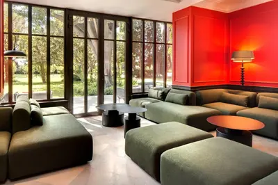 a waiting room with couches and tables and windows at La Jasso Hôtel, Maison de Famille in Carcassonne
