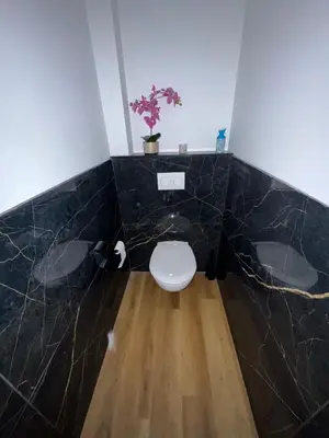 a bathroom with a toilet in a black marble wall at Apparently cozy - wifi - Netflix - air-conditioned in Labastide-dʼAnjou
