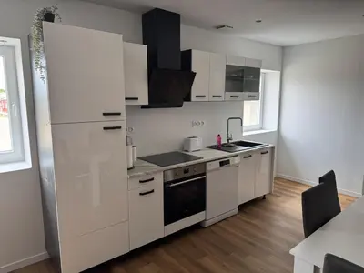 a kitchen with white cabinets and a black appliance at Apparently cozy - wifi - Netflix - air-conditioned in Labastide-dʼAnjou