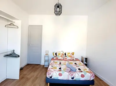 a bedroom with a bed and a white wall at Logement spacieux in Carcassonne