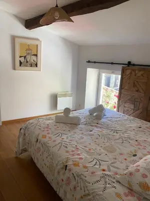 a bedroom with a bed with a comforter on it at Maison entre champs et clochers in Massaguel