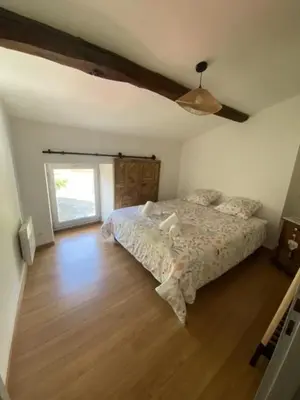 a bedroom with a bed and a wooden floor at Maison entre champs et clochers in Massaguel