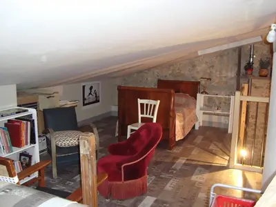 a attic room with a bed and a chair at la cassignolette in Castelnaudary
