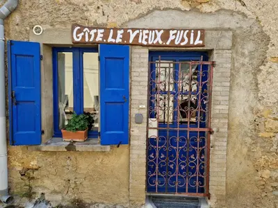 a building with blue doors and a window at Le Vieux Fusil in La Celle-sous-Gouzon