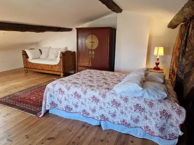 a bedroom with a large bed and a chair at Le Vieux Fusil in La Celle-sous-Gouzon