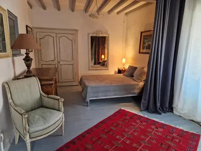 a bedroom with a bed and a chair and a red rug at Le Vieux Fusil in La Celle-sous-Gouzon