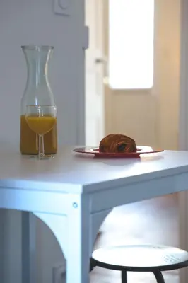 a table with a glass of orange juice and a plate of food at Le Nid Urbain, terrasse, garage et confort in Carcassonne