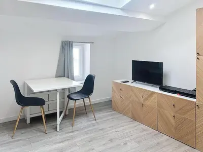 a room with a desk and two chairs and a television at La Suite Lauragaise - Studio climatisé in Villefranche-de-Lauragais
