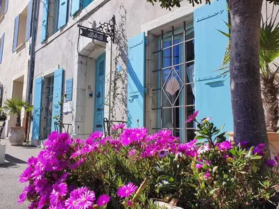 a blue building with purple flowers in front of it at Alcôve Marine in Gruissan