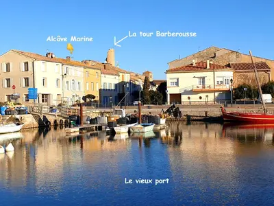 a group of boats docked in a river with buildings at Alcôve Marine in Gruissan