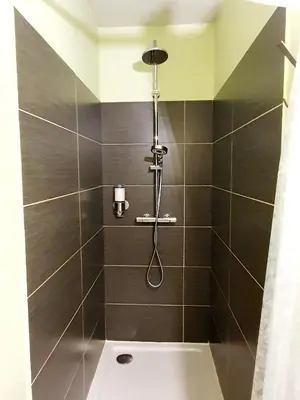 a bathroom with a shower with black tile at Alcôve Marine in Gruissan