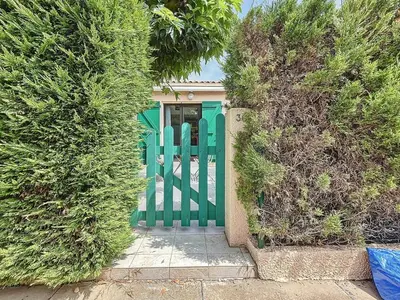 a green gate in front of a house with bushes at La Feuilleraie - Maison de vacance à Leucate in Leucate