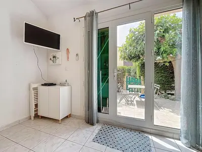 a living room with a sliding glass door with a television at La Feuilleraie - Maison de vacance à Leucate in Leucate