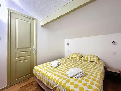 a bedroom with a yellow and white bed with towels on it at La Feuilleraie - Maison de vacance à Leucate in Leucate