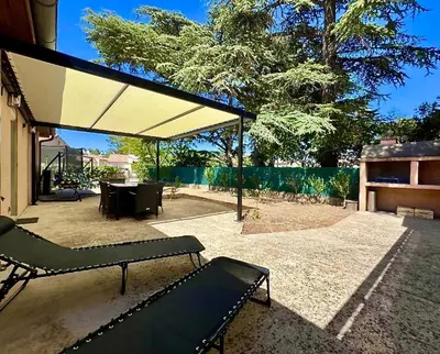 a pavilion with a bench and a table in a yard at Chez Nous, Chez Vous ! in La Redorte