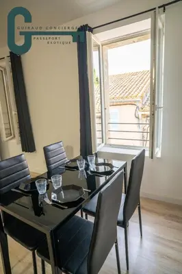a dining room with a table and chairs and a window at Cœur de ville studio lumineux in Castelnaudary