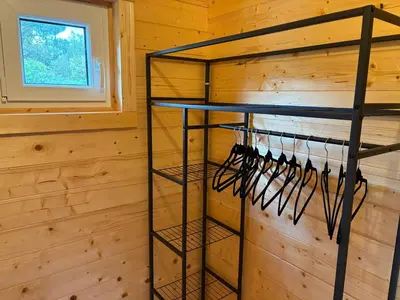 a room with a wooden wall with a rack ofoths at Chalet Chêne-Pin in Boutenac
