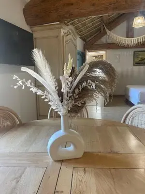 a white vase with feathers on a wooden table at Studio Tahiti du Cloitre in Narbonne