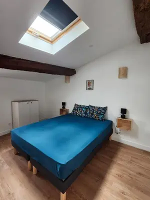 a bedroom with a blue bed and a skylight at Grand T4 lumineux 200 m du port in Castelnaudary