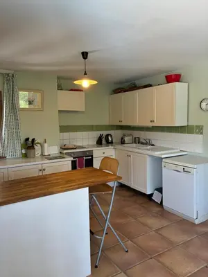 a kitchen with white cabinets and a wooden table at Vacation home with pool in Quillan