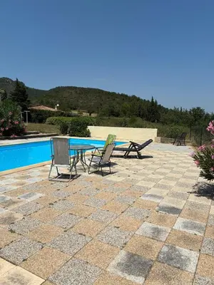 a patio with a table and chairs next to a pool at Vacation home with pool in Quillan