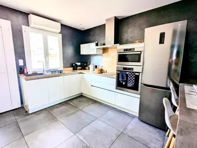 a kitchen with white cabinets and a refrigerator at Évasion à la Villa Sérénité, nature et confort in Port-la-Nouvelle