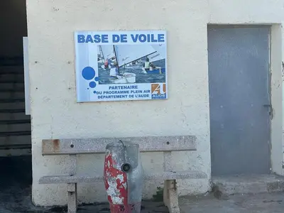 a sign on the side of a building with a bench at Grain de sel in Sigean