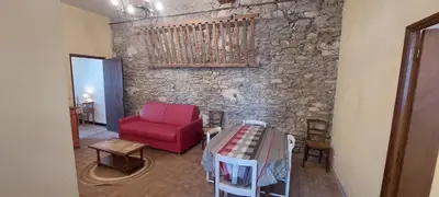 a room with a red chair and a stone wall at Gîte de L'estiu in Cascastel-des-Corbières