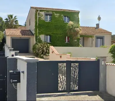 a house with a blue gate and a building at Agréable maison avec jacuzzi in Vinassan