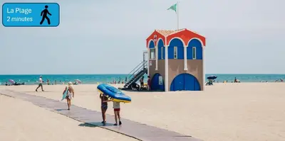 a group of people walking on the beach with a surfboard at Sejour plage Port-la-Nouvelle in Port-la-Nouvelle