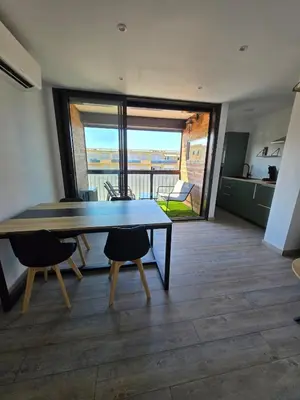 a dining room with a table and chairs and a balcony at Sejour plage Port-la-Nouvelle in Port-la-Nouvelle