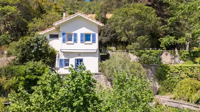 a white house with blue windows and bushes at BB Villa Sainte Marie in Limoux