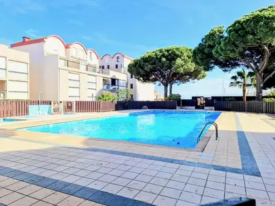 a swimming pool in front of a building at Cocoon sur le port de Gruissan, parking & piscine in Gruissan