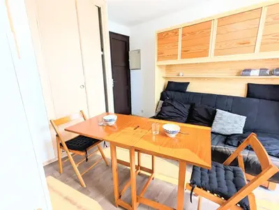 a dining room with a table and a couch at Cocoon sur le port de Gruissan, parking & piscine in Gruissan