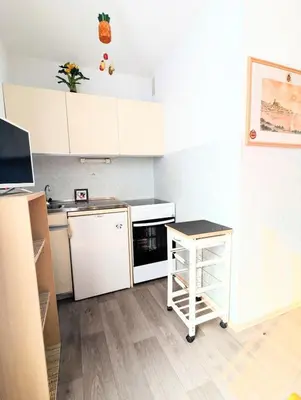 a small kitchen with white cabinets and a counter at Cocoon sur le port de Gruissan, parking & piscine in Gruissan