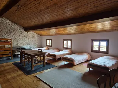 a room with beds and a table in a building at La Maison de Léonie in Camurac
