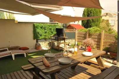 a patio with a wooden table and an umbrella at Gruissan Terrasse jardin cosy et au calme in Gruissan