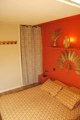 a bedroom with a bed with an orange wall at Gruissan Terrasse jardin cosy et au calme in Gruissan